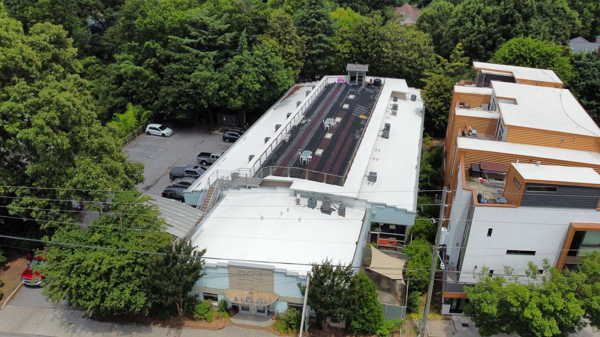 Completed commercial TPO roof with walkable paver system — front drone view