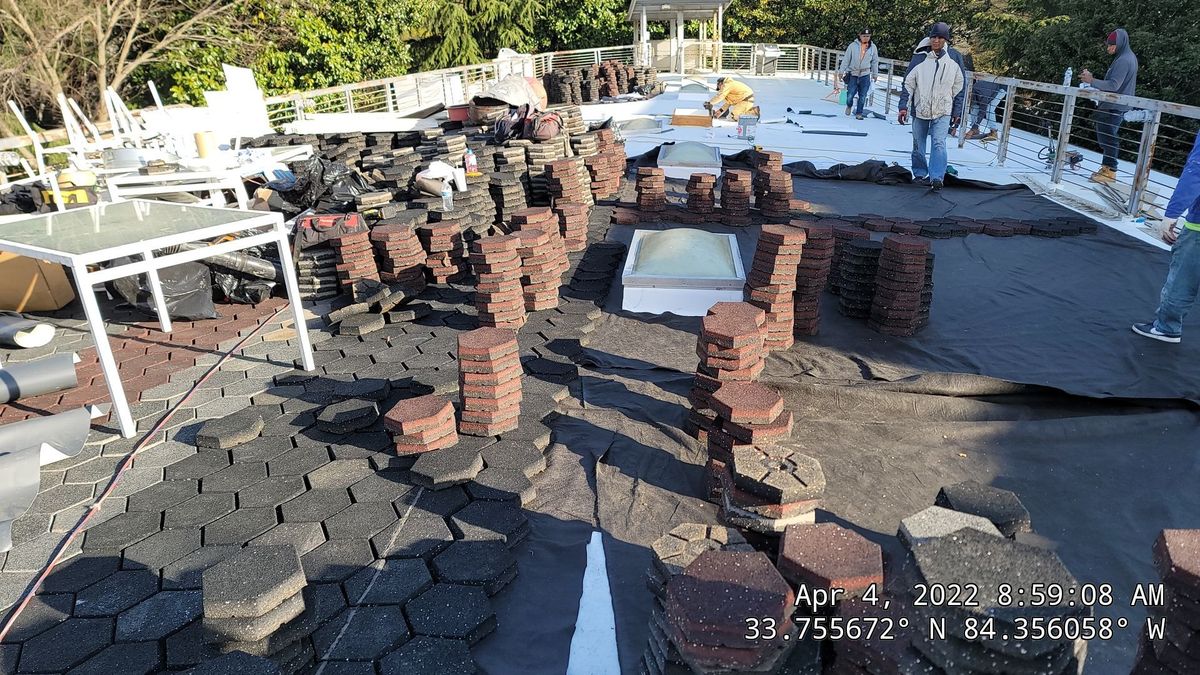 Commercial TPO roof during installation — membrane application and paver staging