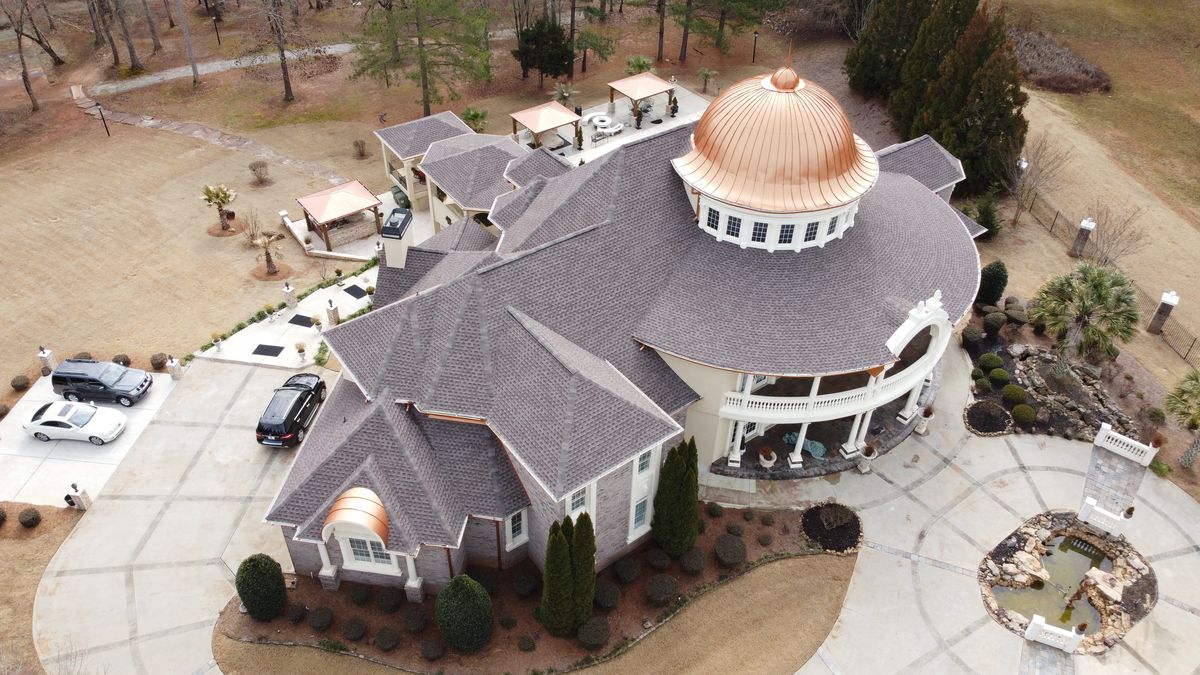 Estate home with finished Mission Brown roof and custom copper dome — drone view